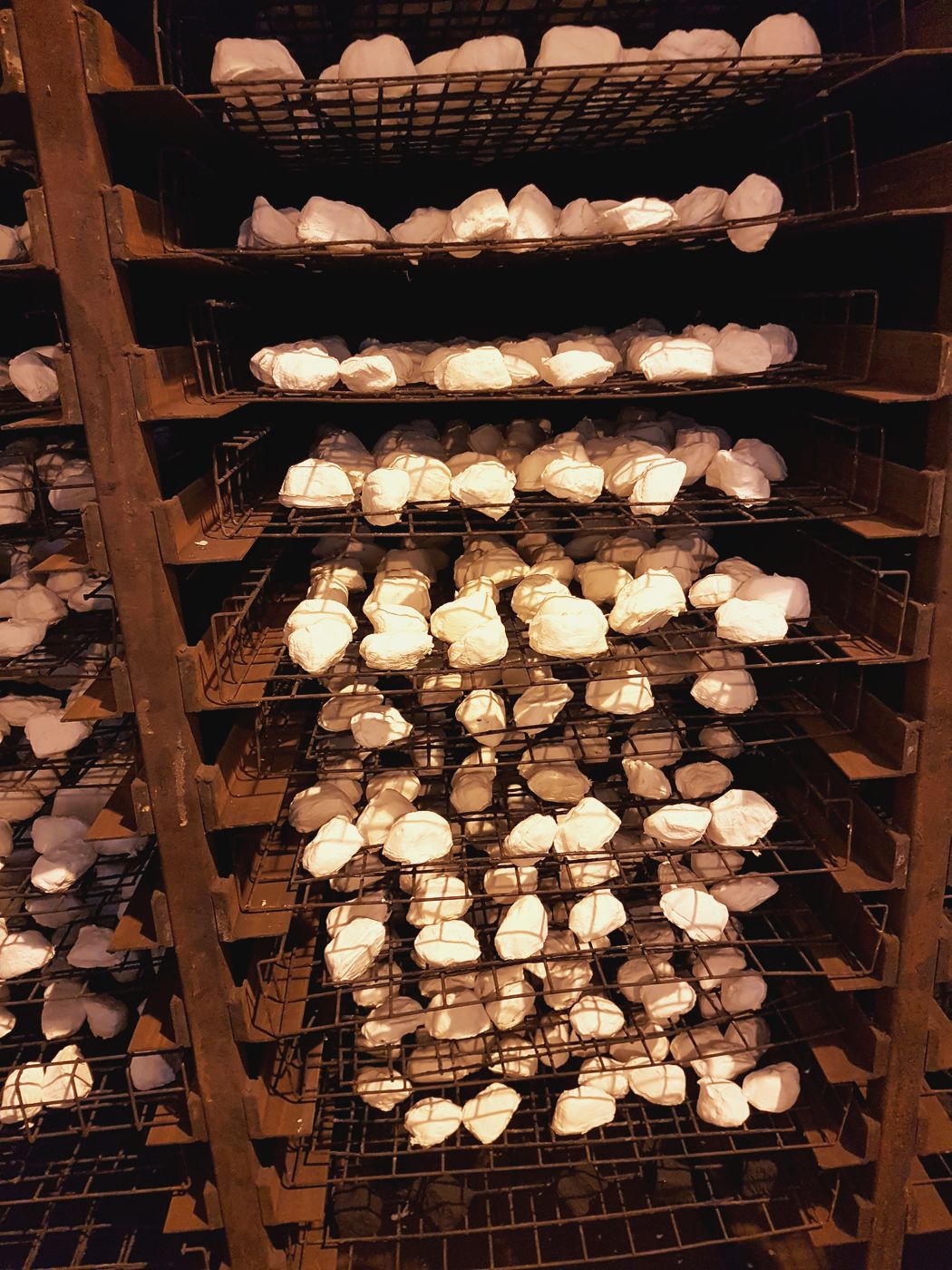 Freshly manufactured white ceramic fuel-bed pieces drying on industrial wire racks in The Stove Wizard factory.